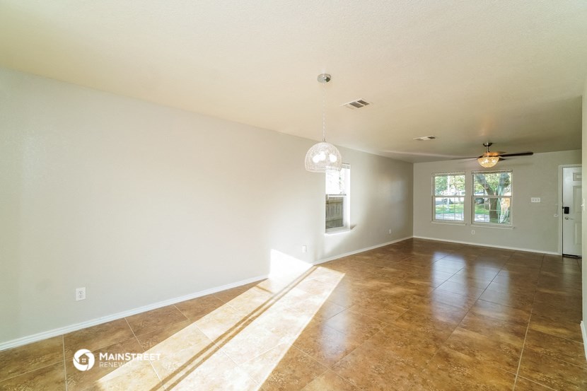 the spacious living room and dining room with white walls and wood floors