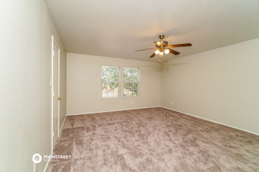 an empty living room with a ceiling fan and a window