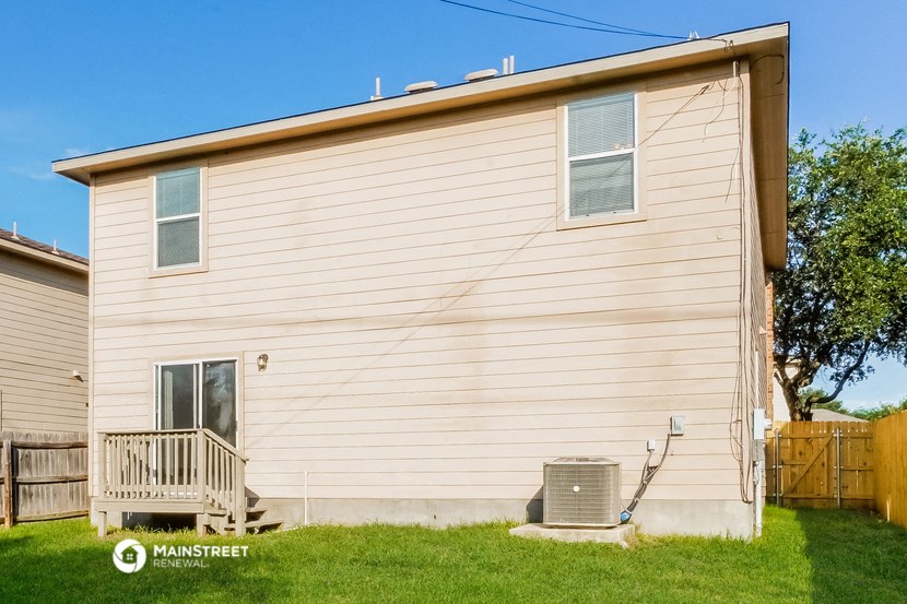 the side of a white house with a wooden fence and a deck
