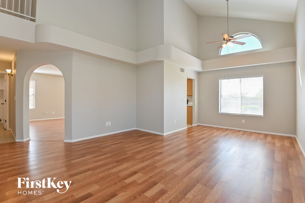 an empty living room with hardwood floors and a ceiling fan