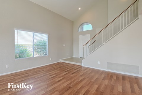 the living room and entryway of a house with hardwood floors and a staircase