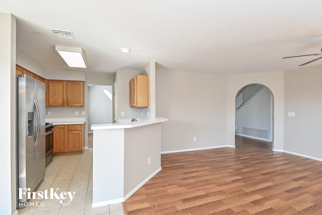 an open kitchen and living room with wood flooring and stainless steel appliances