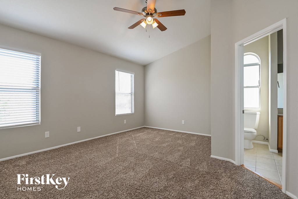 an empty room with a ceiling fan and a toilet