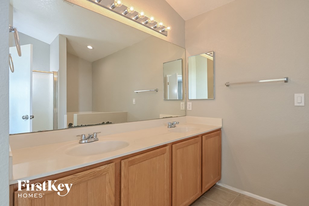 the master bathroom has a large vanity with a large mirror and two sinks
