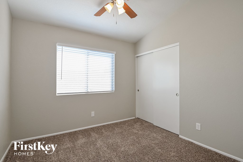 a bedroom with a ceiling fan and a door to a closet