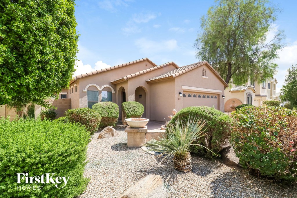 A Spanish style home with a gravel driveway and landscaping.