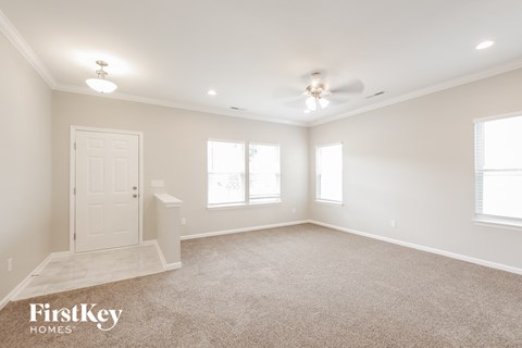 a spacious living room with a ceiling fan and a white door
