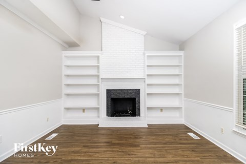 a living room with a fireplace and white shelves
