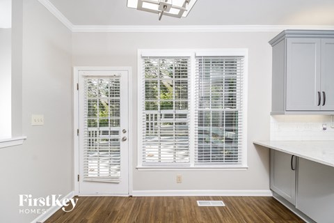 a kitchen with white cabinets and a door with white plantation shutters