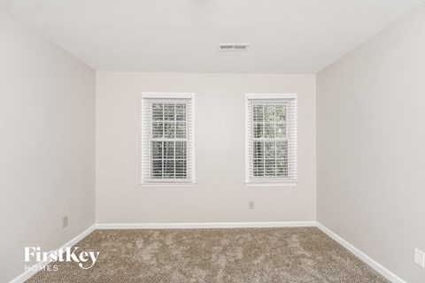 a bedroom with two windows and a carpeted floor