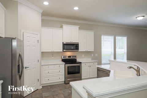 A kitchen with white cabinets and a stainless steel refrigerator.