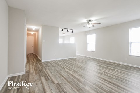 A spacious room with wooden flooring and a ceiling fan.