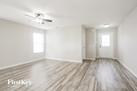 A spacious room with a wood floor and a ceiling fan.