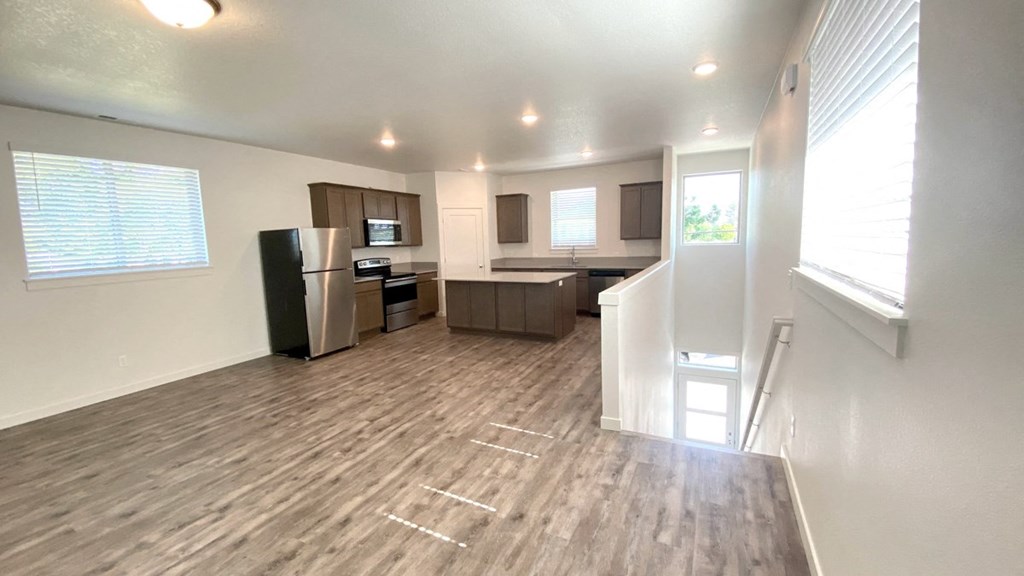 A spacious living room with a kitchen area in the background.