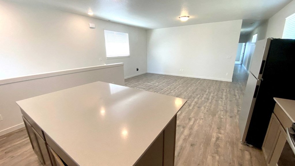 A kitchen with a white countertop and wooden flooring.