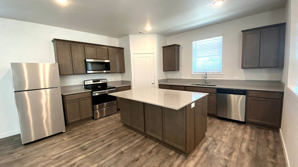 A kitchen with brown cabinets and a stainless steel refrigerator.