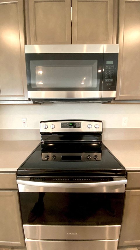 A black stove top oven with a silver microwave above it.