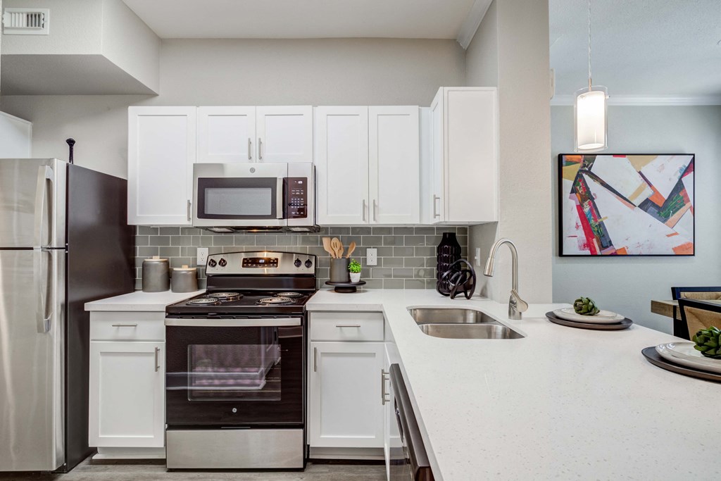 a kitchen with white cabinets and stainless steel appliances and a sink