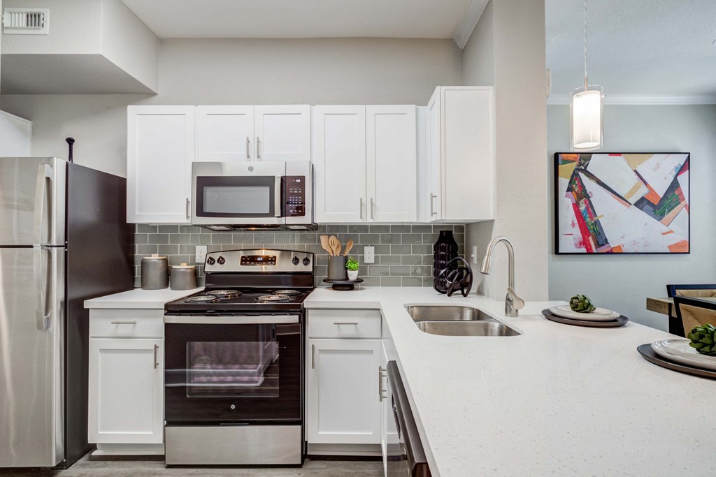 a kitchen with white cabinets and stainless steel appliances and a sink