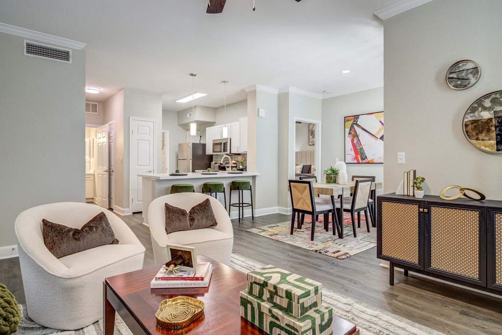 a living room and dining room with a kitchen in the background