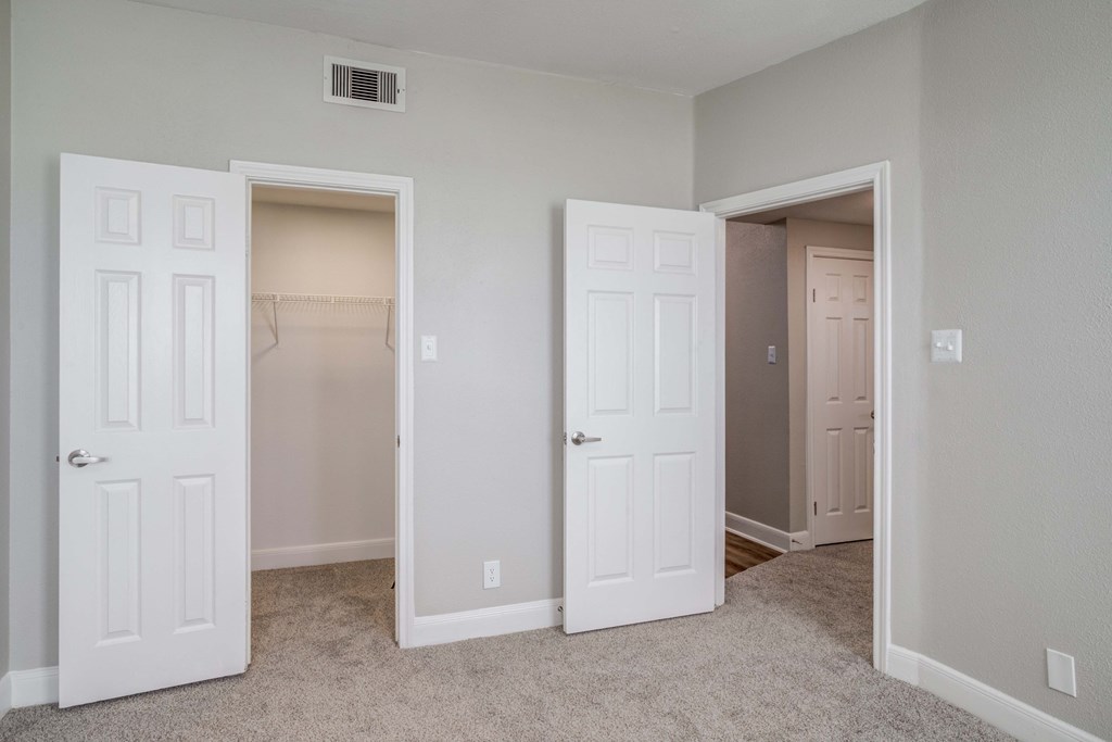 an empty bedroom with two doors and a closet