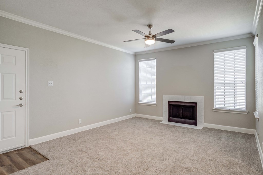an empty living room with a fireplace and a ceiling fan