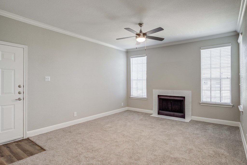 an empty living room with a fireplace and a ceiling fan