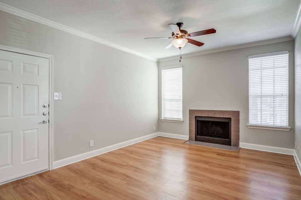 an empty living room with a fireplace and a ceiling fan