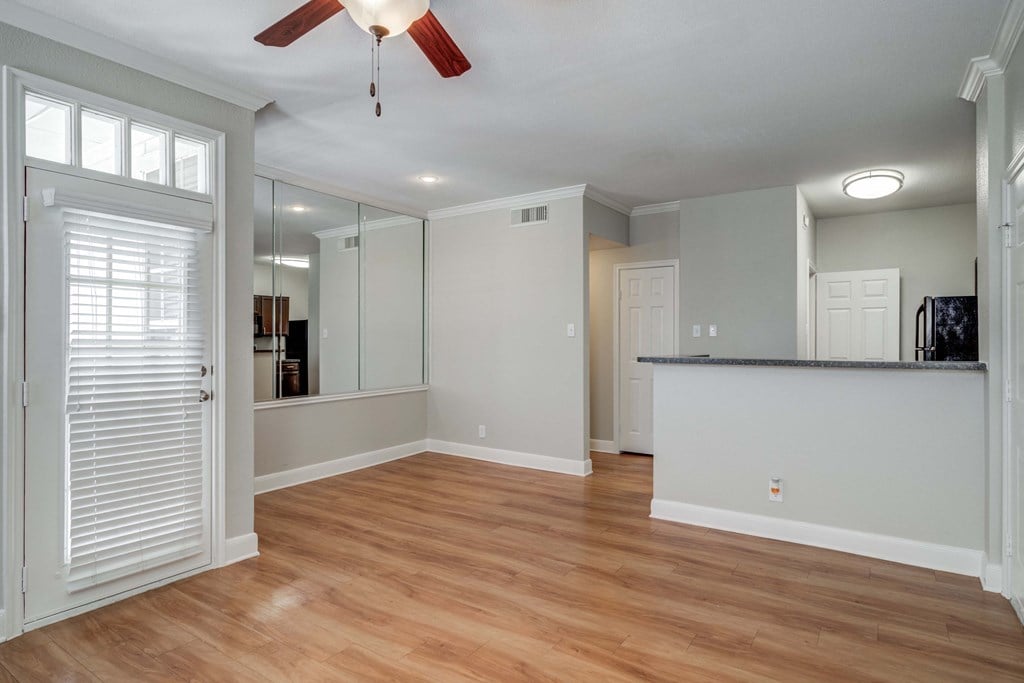 an empty living room with a door to a kitchen