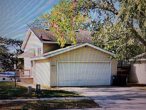 A house with a white garage door and a tree in front.