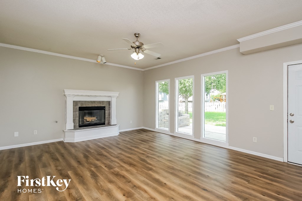an empty living room with a fireplace and a ceiling fan