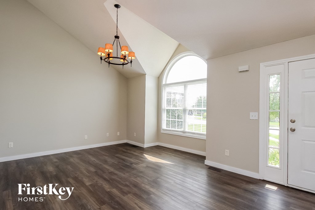 an empty living room with a large window and a chandelier