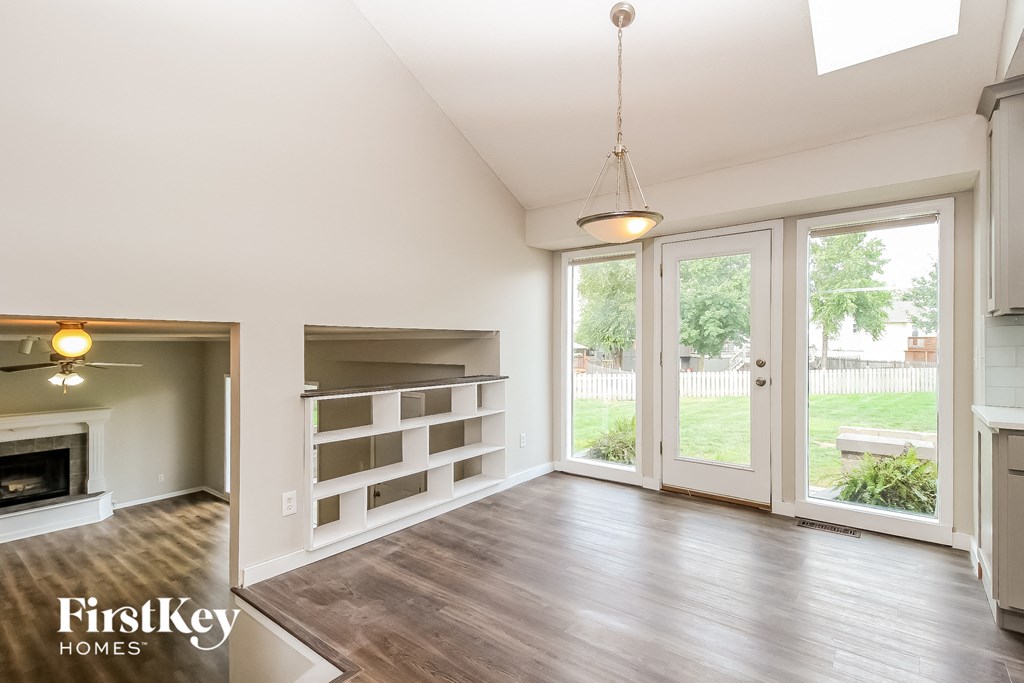 an empty living room with a fireplace and a bookshelf