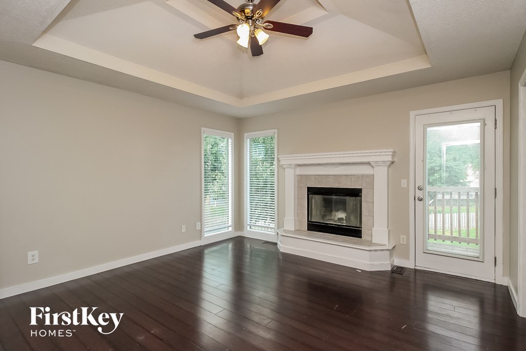 an empty living room with a fireplace and a ceiling fan