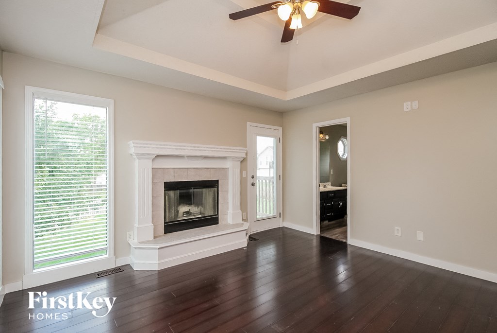 an empty living room with a fireplace and a ceiling fan