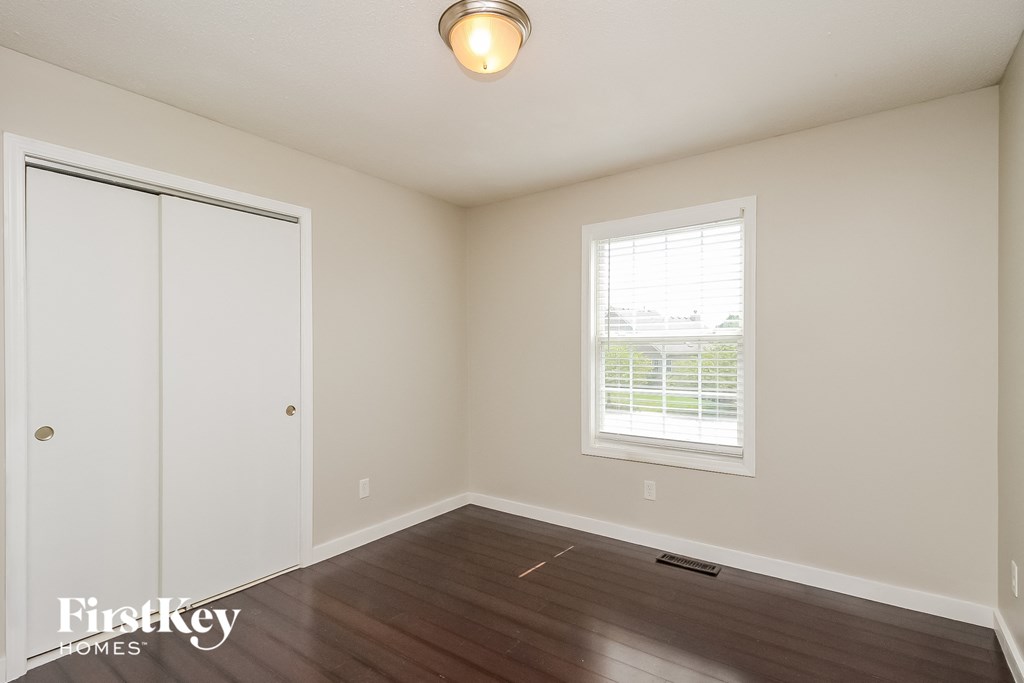a bedroom with a hardwood floor and a window and a closet
