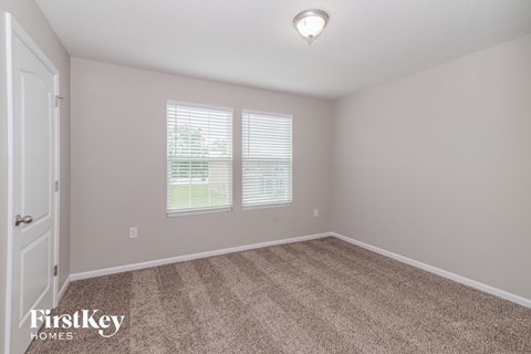 a bedroom with carpet and two windows and a door