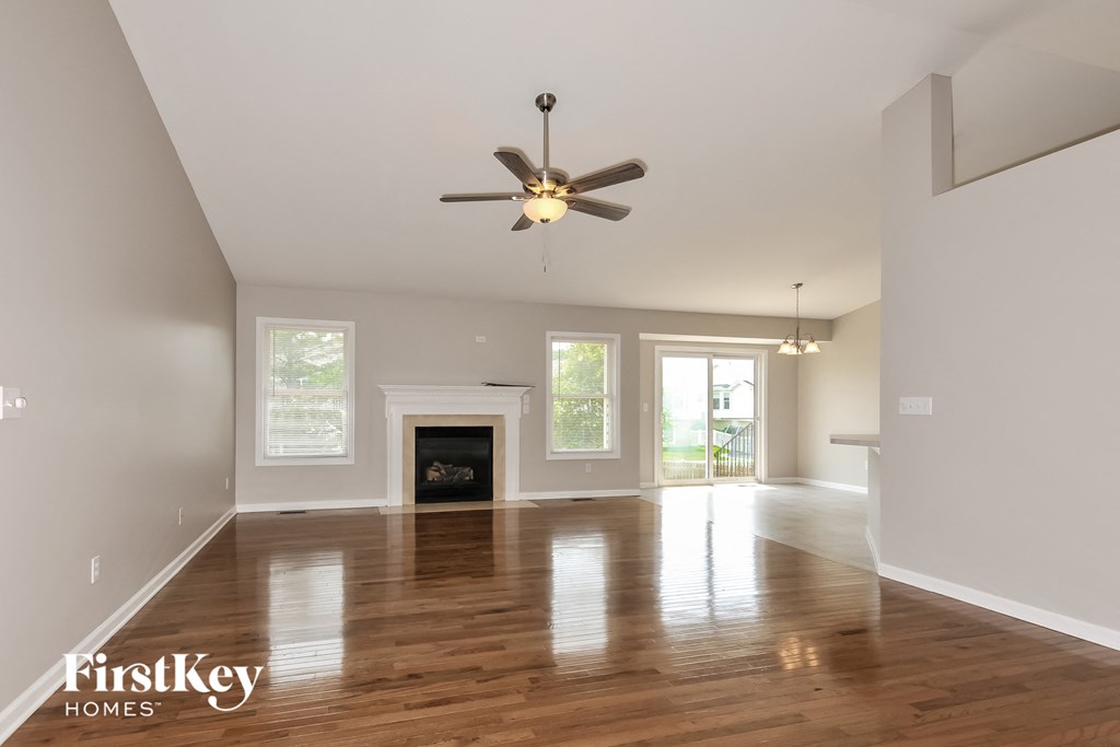 an empty living room with a ceiling fan and a fireplace