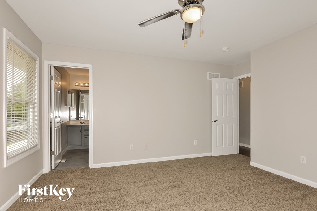 a bedroom with a ceiling fan and a door to a bathroom