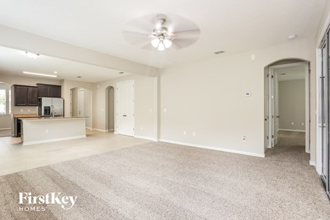an empty living room and kitchen with a ceiling fan