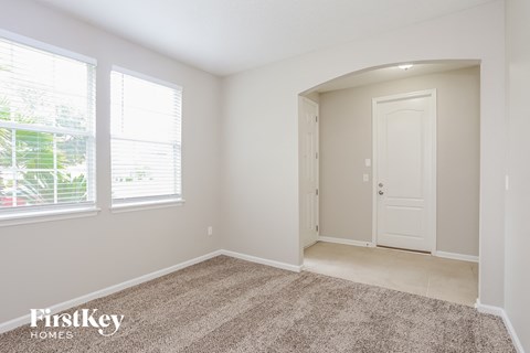 a bedroom with a door and two windows and a carpeted floor