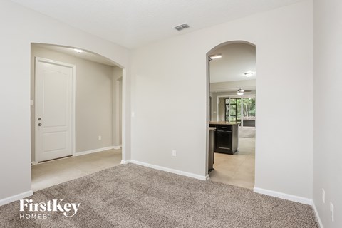 a living room with a carpet and a door to a kitchen