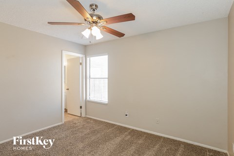 the spacious living room with ceiling fan and carpet