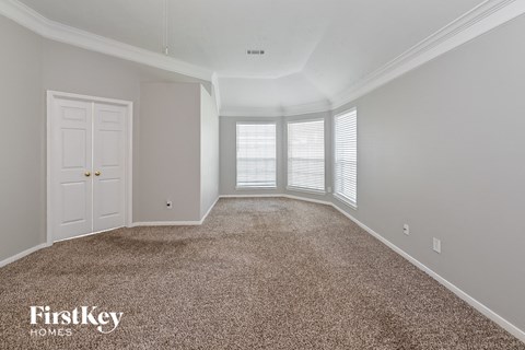 a spacious living room with carpet and a white door