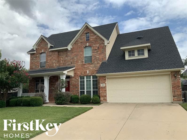 a brick house with a black roof and a driveway