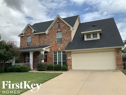 a brick house with a black roof and a driveway