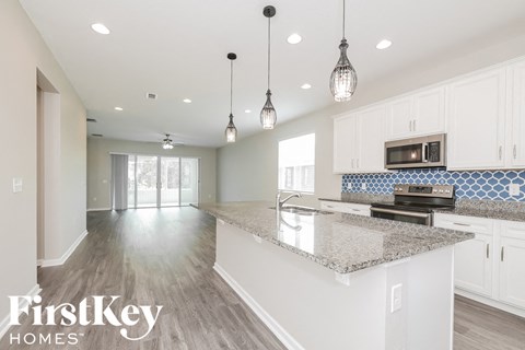 A kitchen with a granite countertop and a microwave on top.