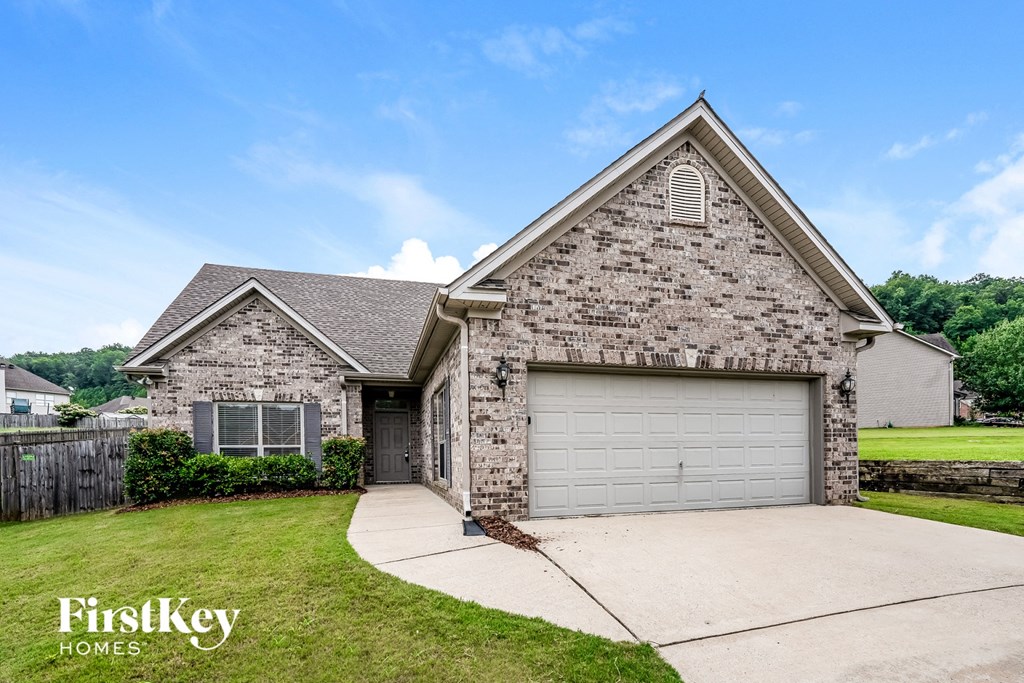 a brick house with a garage door and a lawn