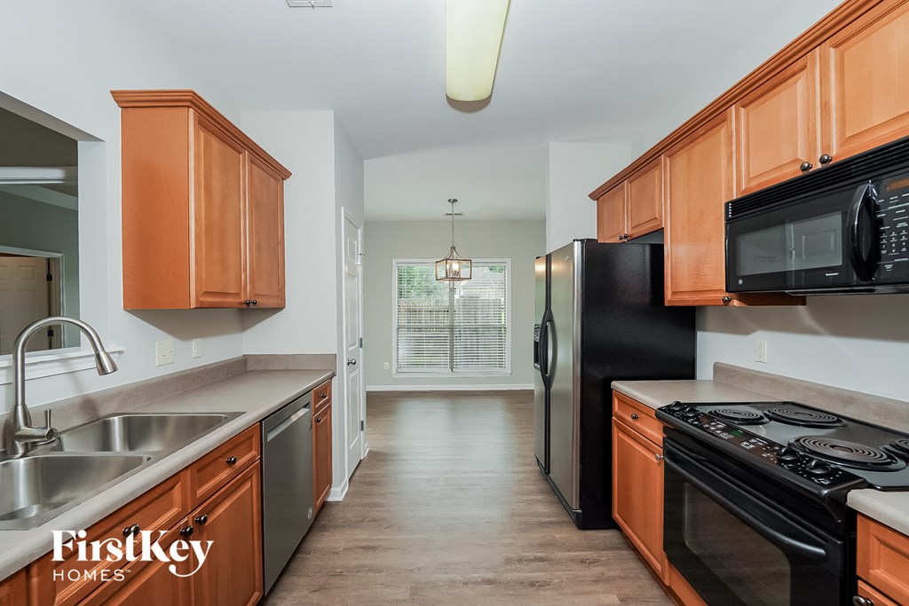 a kitchen with wooden cabinets and stainless steel appliances and a black refrigerator