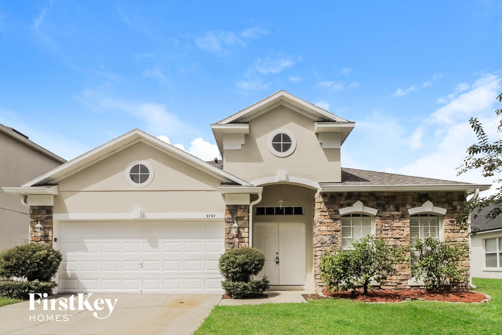 a beige house with a garage door and a lawn
